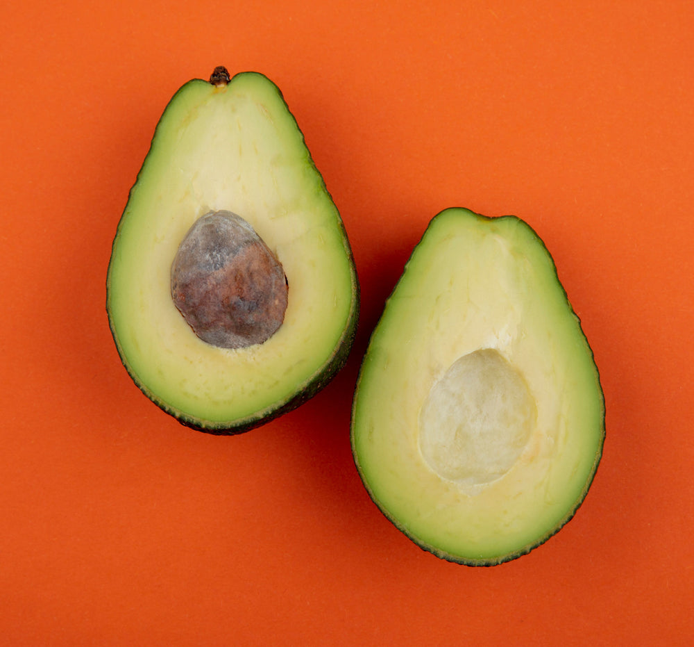 Orange backdrop with a halved avocado, top view